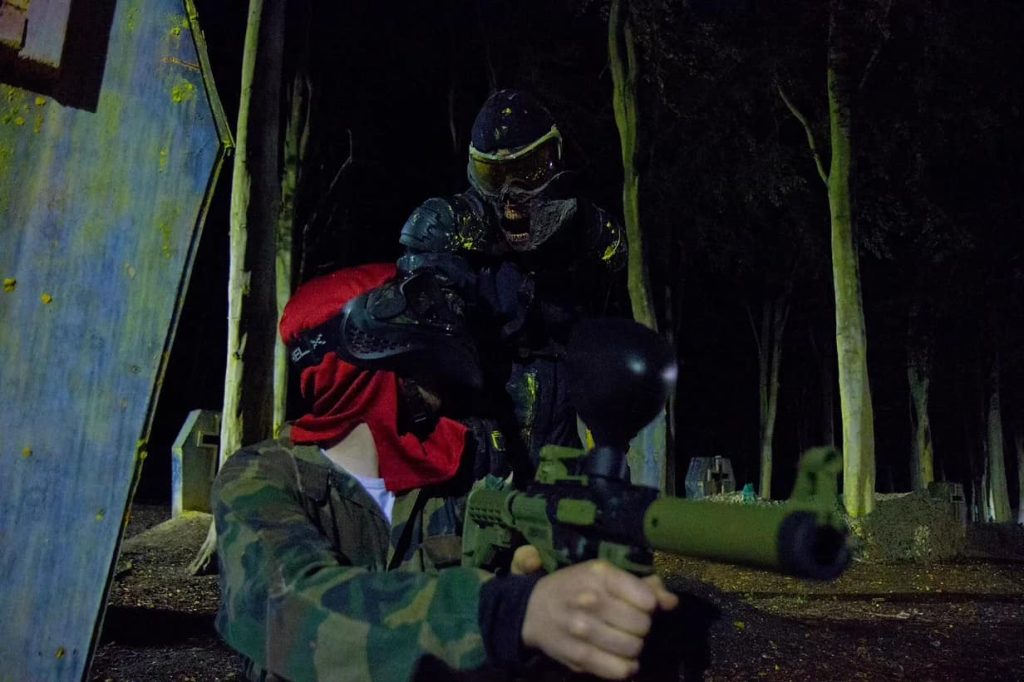 Zombie character sneaking up on paintball player during a paintball nights game